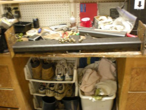 1993 Ford Bronco - A cluttered workbench holds metal components and various items, including shoes and laundry.