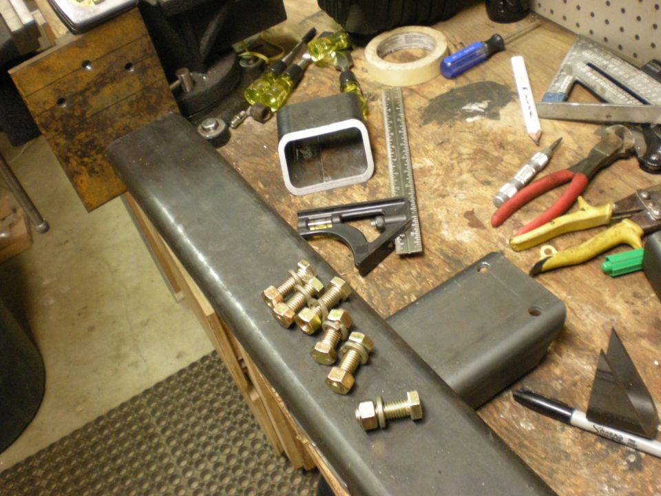 Bolts and nuts on a metal bar with various tools on a workbench