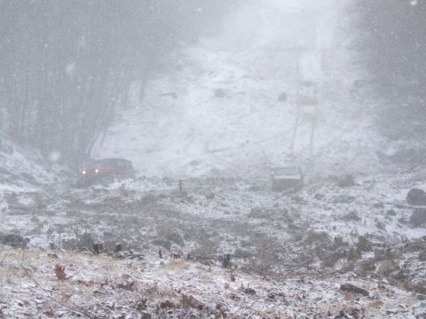 1976 Toyota Land Cruiser - Two vehicles navigate a snowy hillside during a snowstorm.