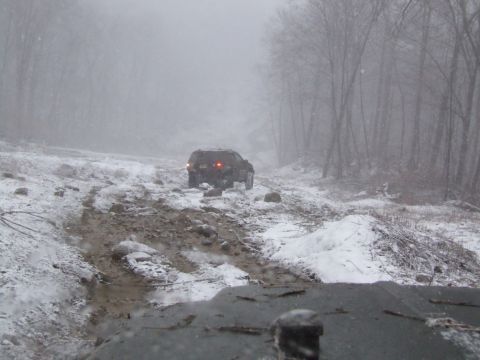 1976 Toyota Land Cruiser - A vehicle navigates a challenging, snow-covered path through a wooded area.