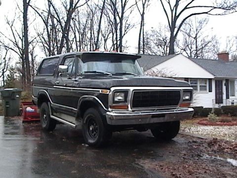 1990 Ford Bronco - This black SUV, likely a Ford Bronco from the late 1970s, is parked in a driveway on a cloudy day.