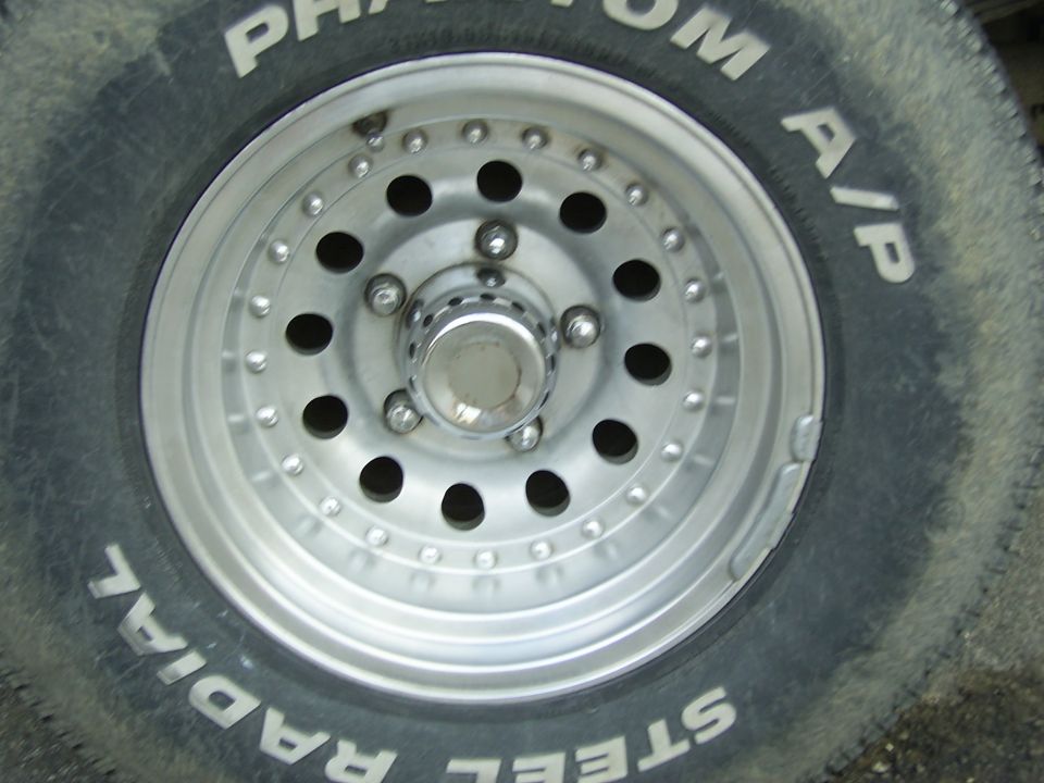 Aluminum alloy wheel with 12 lug nuts and 12 circular holes, mounted on a tire with white lettering