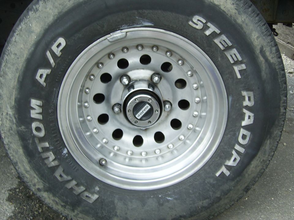 Close-up of a steel radial tire with 'Phantom A/P' and 'Steel Radial' text, mounted on a multi-hole aluminum wheel with a Warn locking hub