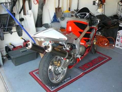 1978 Ford Bronco - A red and silver Honda motorcycle is parked on a mat in a garage, with various tools and equipment visible in the background.