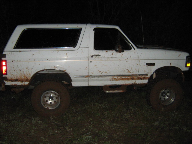 White lifted full-size SUV with mud splatter photographed at night