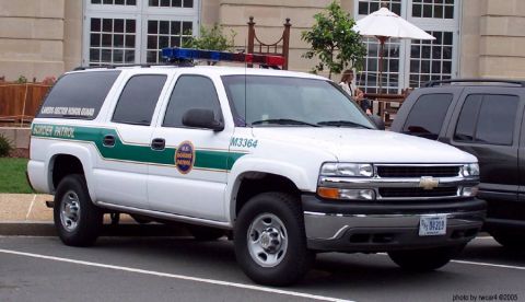 1991 Ford Crown Victoria - A white Chevrolet Suburban, marked for Border Patrol, is parked next to another SUV.
