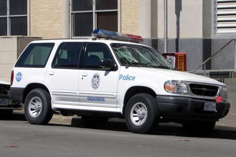 1991 Ford Crown Victoria - This police SUV, likely a 1995 Ford Explorer, is parked near a building.