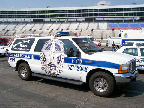 1991 Ford Crown Victoria - A Dallas Police SUV is parked in front of a stadium, with other emergency vehicles visible in the background.