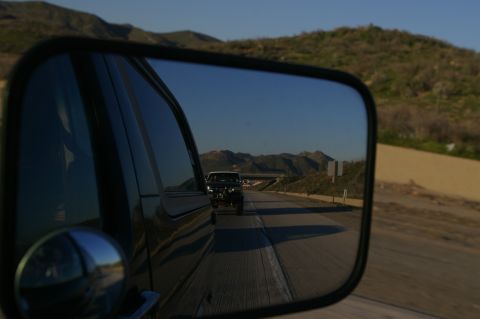 1986 Ford Bronco - View of a highway and mountains reflected in the side mirror of a vehicle.