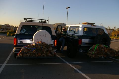 1986 Ford Bronco - Two Ford Broncos are parked side-by-side, each carrying a load of firewood on a rear rack.