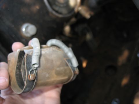 1949 Chevrolet C/K Pickup - A close-up shows a person holding a weathered automotive component, possibly from an engine bay.