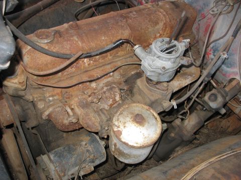 1949 Chevrolet C/K Pickup - Close-up view of a heavily rusted engine compartment, showing the carburetor and various hoses.