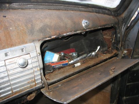 1949 Chevrolet C/K Pickup - Interior view of a rusty glove box containing various old parts and spark plugs.