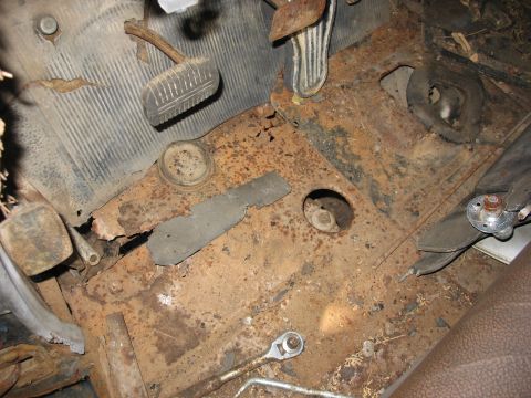 1949 Chevrolet C/K Pickup - The interior floor shows extensive rust damage and exposed metal, with pedals and a wrench visible.