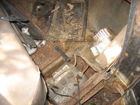 1949 Chevrolet C/K Pickup - The interior of a vehicle shows a battery, floor mat, and signs of rust and debris.