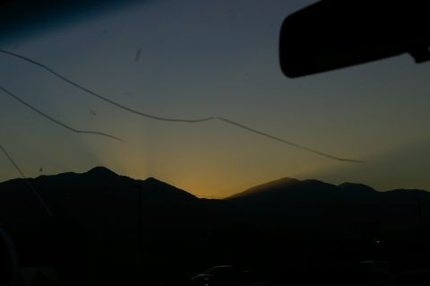 1986 Ford Bronco - Sunset viewed through a cracked windshield, with silhouetted mountains in the distance.