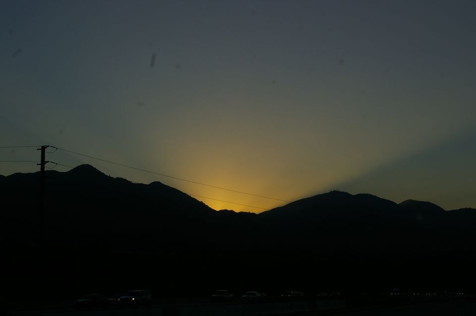 Sunset over mountains with cars on highway