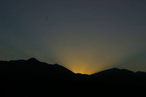 1986 Ford Bronco - Sun rays emanate from behind dark mountain peaks at dusk.