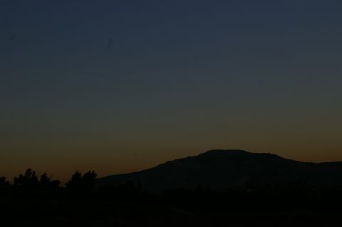1986 Ford Bronco - A vast mountain range is silhouetted against a twilight sky, with trees in the foreground.