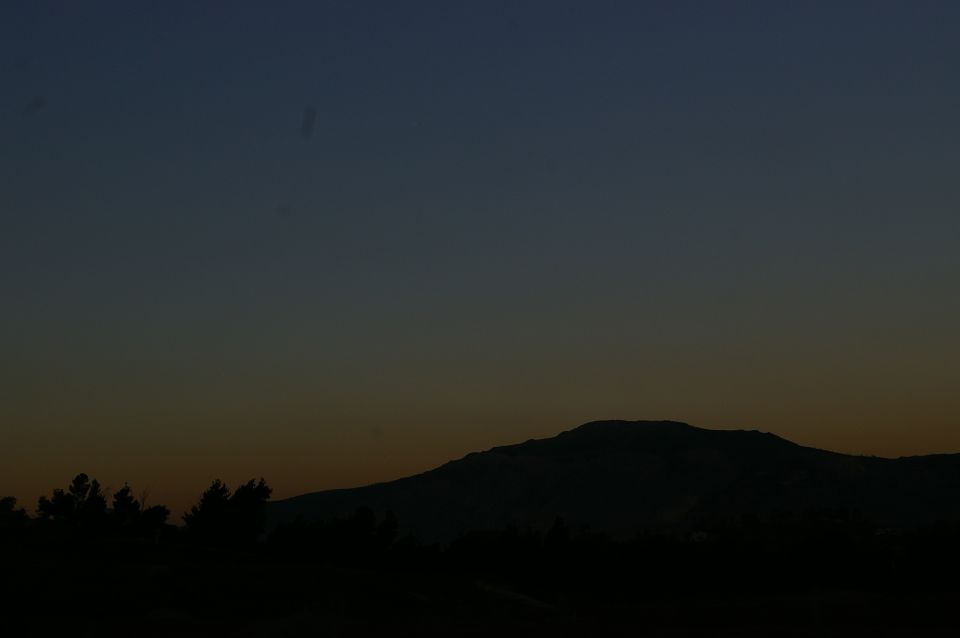Silhouette of a mountain range against a dark blue and orange gradient sky at dusk