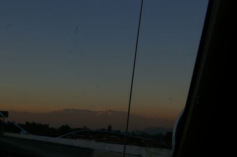 1986 Ford Bronco - Sunset view from inside a vehicle, with distant mountains and trees silhouetted against the twilight sky.