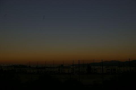 1986 Ford Bronco - The sky transitions from deep blue to orange over a distant town and a fence.