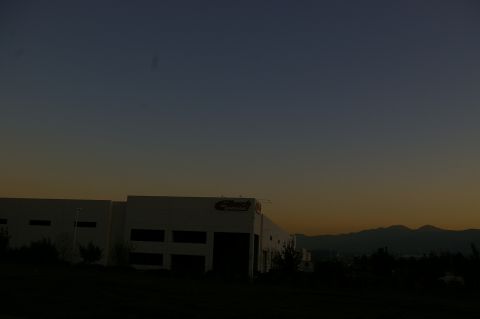 1986 Ford Bronco - A building with a logo is visible against the gradient of a twilight sky, with mountains in the distance.
