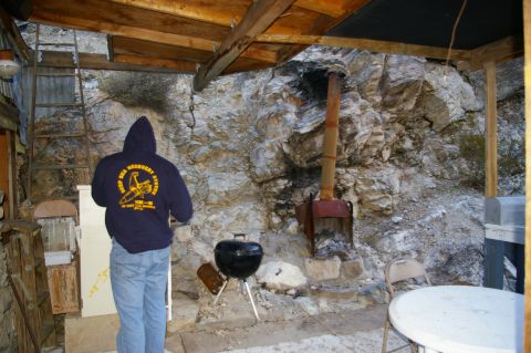 1986 Ford Bronco - A person stands in a rustic outdoor area with a rocky backdrop, wearing a dark hoodie with a yellow graphic and text.