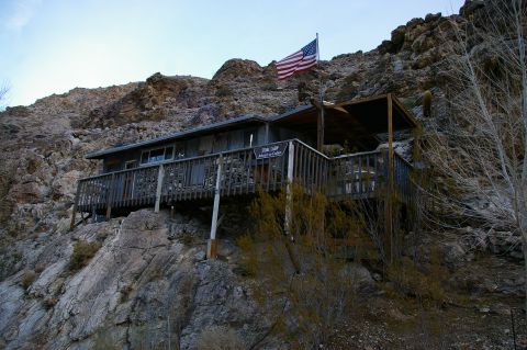 1986 Ford Bronco - Cabin on a rocky hillside, flying the American flag.