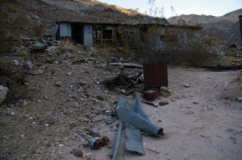 1986 Ford Bronco - An old, weathered structure sits in a desolate, rocky environment, surrounded by debris and sparse vegetation.
