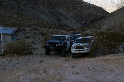 1986 Ford Bronco - A black 1986 Ford Bronco and a white Toyota SUV are parked in a dusty desert canyon.