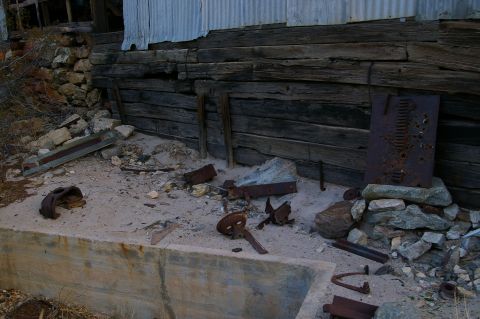 1986 Ford Bronco - A collection of discarded metal objects and rubble lies on the ground near an old building.