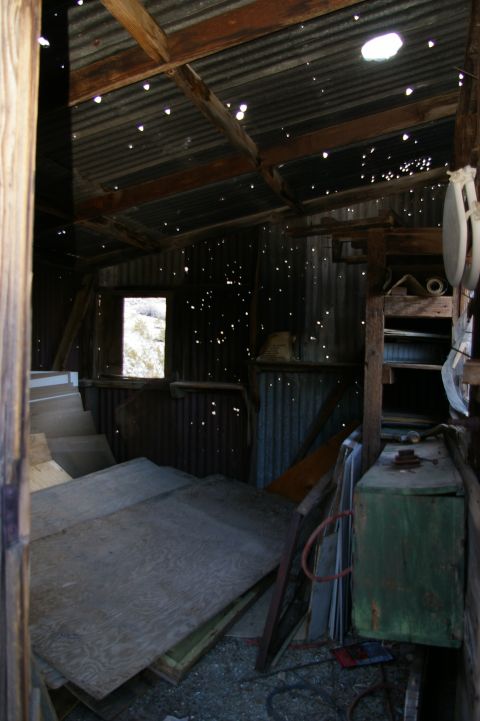 1986 Ford Bronco - The interior of a dilapidated structure, likely an old shed or workshop, shows signs of decay with light filtering through numerous holes i…