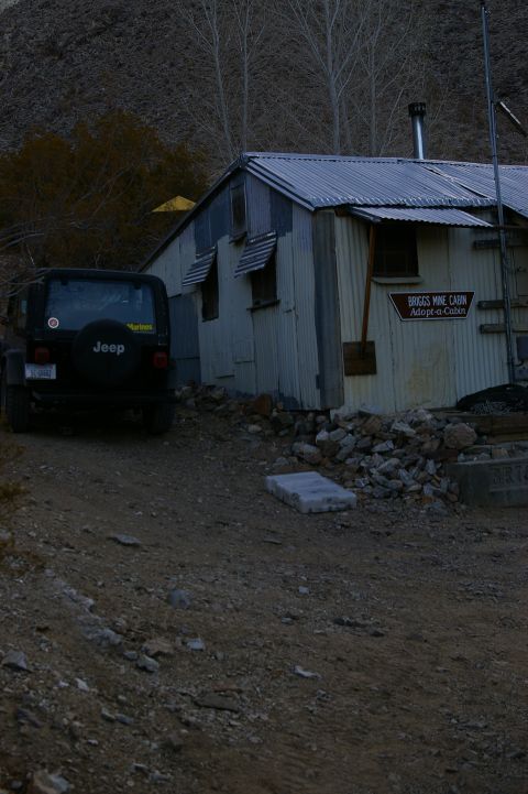 1986 Ford Bronco - A Jeep Wrangler sits parked on a dirt road beside the Briggs Mine Cabin.