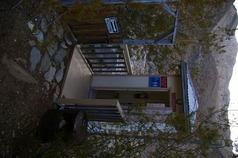 1986 Ford Bronco - A remote outdoor restroom facility is situated in a rocky, arid landscape.