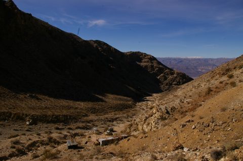 1986 Ford Bronco - Abandoned structures sit in a dry, rocky canyon under a clear blue sky.