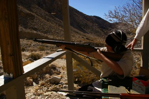 1986 Ford Bronco - Shooting a rifle at an outdoor range with mountains in the background. Winchester ammo box nearby.
