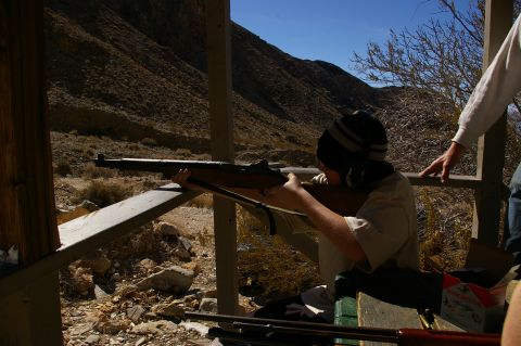 1986 Ford Bronco - A person practices shooting a rifle from a covered outdoor structure with a mountainous backdrop.