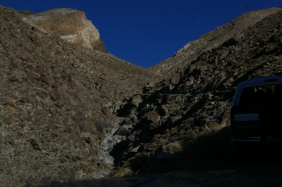 SUV parked on a dirt road in a canyon with rocky hillsides
