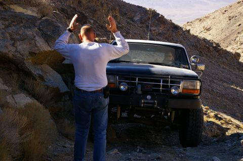 1986 Ford Bronco - A man stands in front of a black Ford Bronco on a steep, rocky trail.