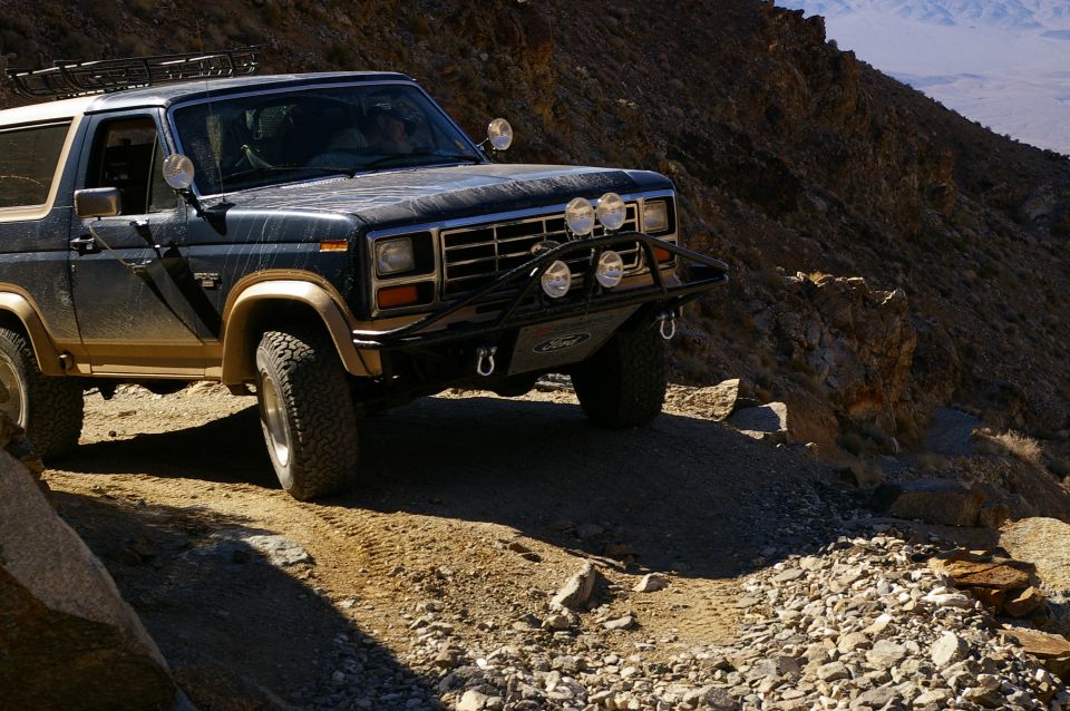 1986 Ford Bronco on dirt road, 3q-front view, dark blue and tan