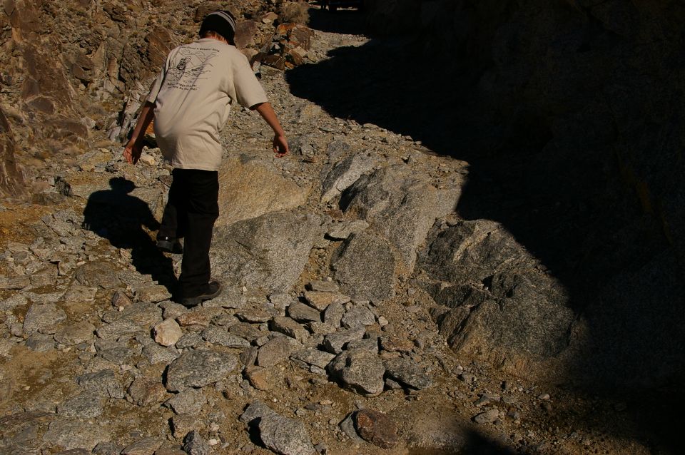 Person in t-shirt and black pants walking on a rocky path