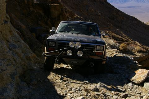 1986 Ford Bronco - Ford Bronco tackling a challenging rocky trail in a desert landscape.