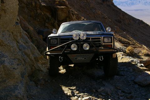 1986 Ford Bronco - This Ford Bronco navigates a challenging, rocky terrain with a steep cliff face to its left.