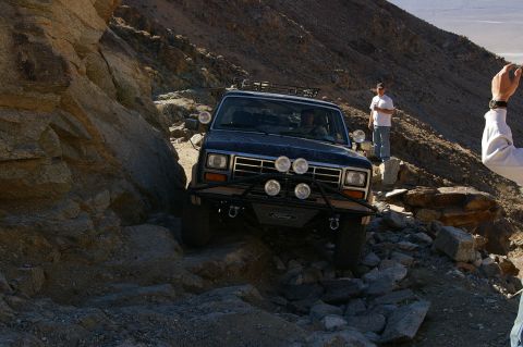 1986 Ford Bronco - A Ford Bronco maneuvers through a challenging, rocky terrain, with onlookers observing the difficult passage.