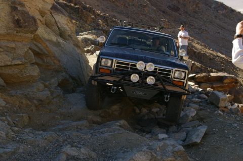 1986 Ford Bronco - A Ford Bronco navigates a challenging rocky terrain, its front end angled towards the viewer.