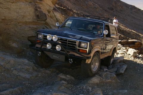 1986 Ford Bronco - This Ford Bronco navigates a rocky desert terrain, its off-road capabilities with a custom brush guard and auxiliary lights.