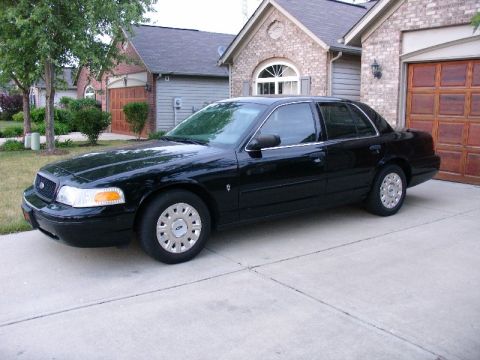 2003 Ford Crown Victoria - This black 2003 Ford Crown Victoria is parked in a suburban driveway, its classic sedan profile.