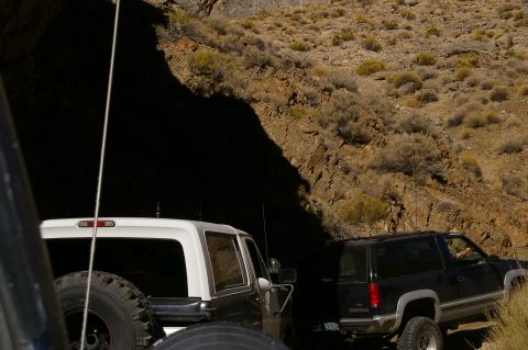 1986 Ford Bronco - A 1986 Ford Bronco navigates a rocky off-road trail, with another SUV visible behind it.