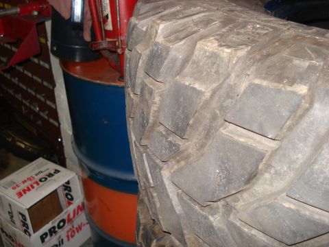 1994 Ford Bronco - A large off-road tire is shown next to storage barrels and oil boxes.
